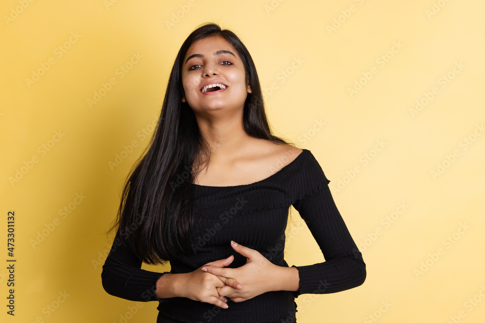 Obraz premium Emotional young adorable cute girl, student in black blouse posing isolated on yellow color studio backgroud