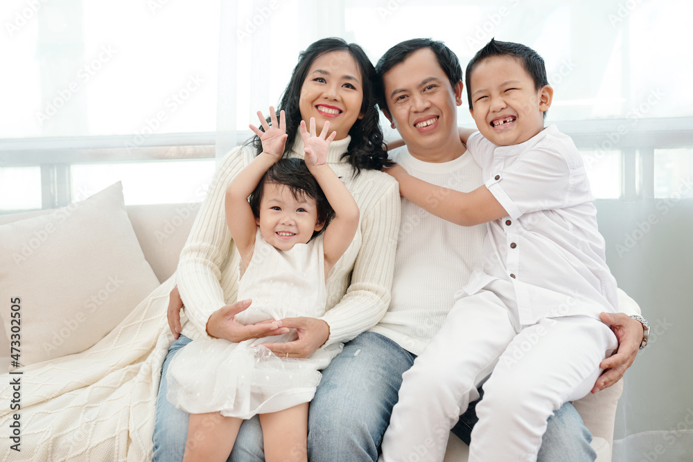 Portrait of happy married couple with two children sitting on sofa at home