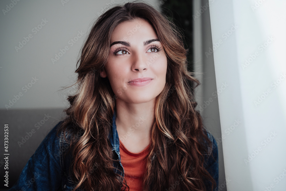 Beautiful woman with long hair contemplating by window at home Beautiful woman with long hair contemplating by window at home