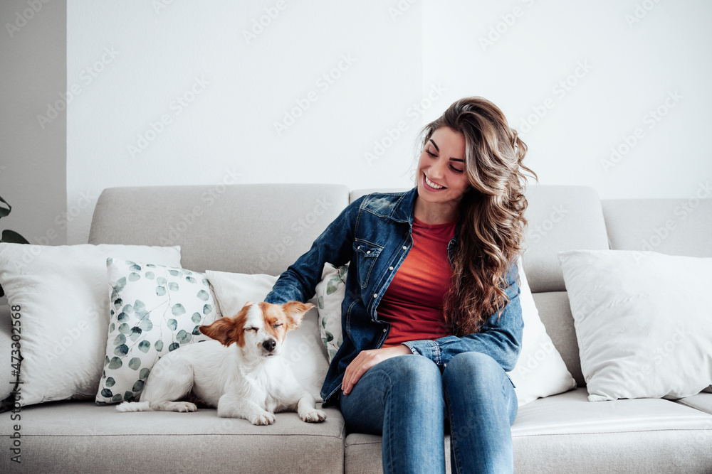 Smiling woman with long hair stroking dog on sofa Smiling woman with long hair stroking dog on sofa