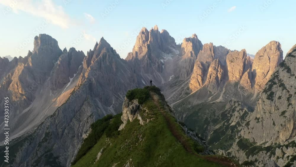 Man standing in top of a mountain watching sunset in Tre Cime di Lavaredo, Dolomites Man standing in top of a mountain watching sunset in Tre Cime di Lavaredo, Dolomites