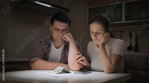 Canvas-taulu Upset couple calculating family budget and looking on few money banknotes on tab