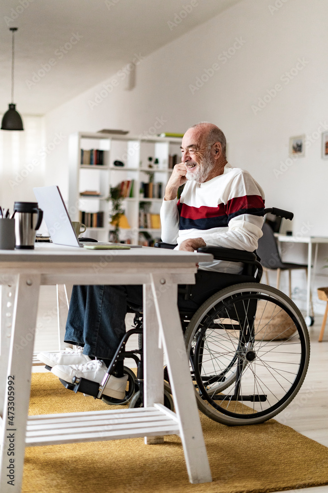 Disabled businessman attending video call through laptop at home Disabled businessman attending video call through laptop at home