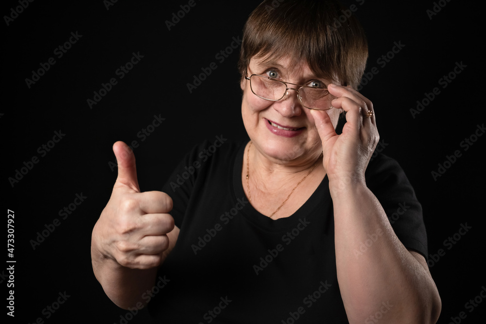 An elderly woman on a black background shows like.
