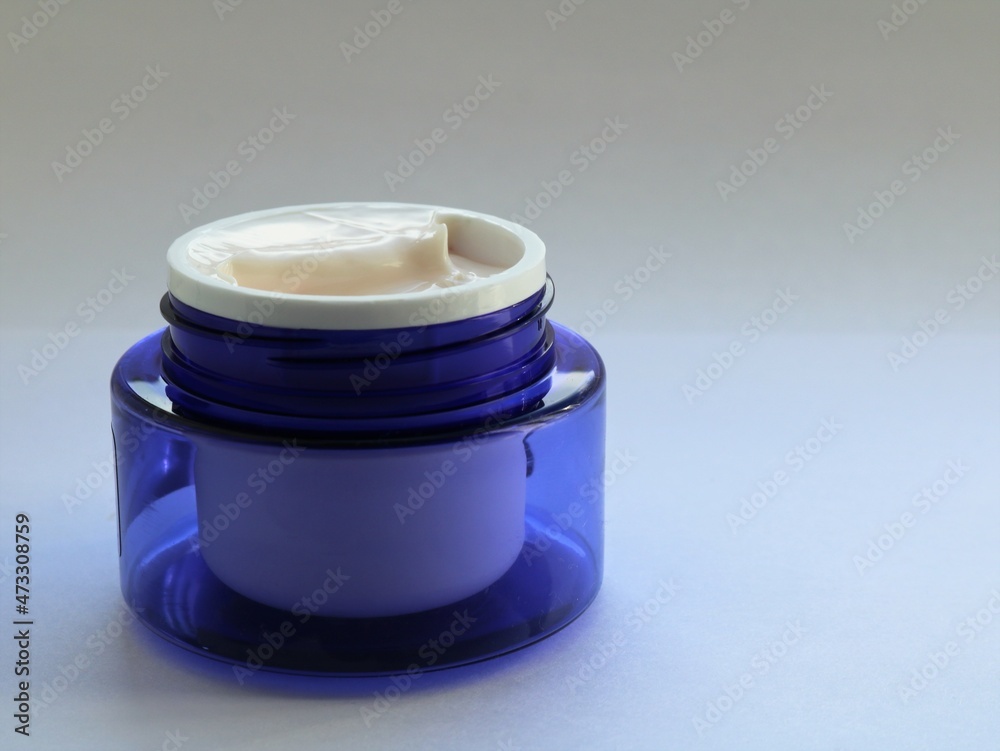 new open blue jar with gentle light skin cream on a white blank background, an example of skin care cosmetics for women isolated on a light backdrop, cream in a plastic jar new open blue jar with gentle light skin cream on a white blank background, an example of skin care cosmetics for women isolated on a light backdrop, cream in a plastic jar