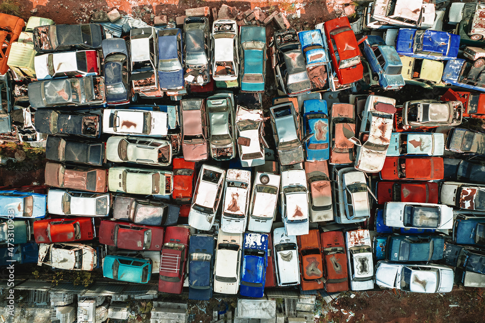 Obraz premium Aerial view of a Soviet automobile dump from a drone. Shooting from above at heaps of rusty cars. Abandoned Russian cars awaiting disposal and recycling