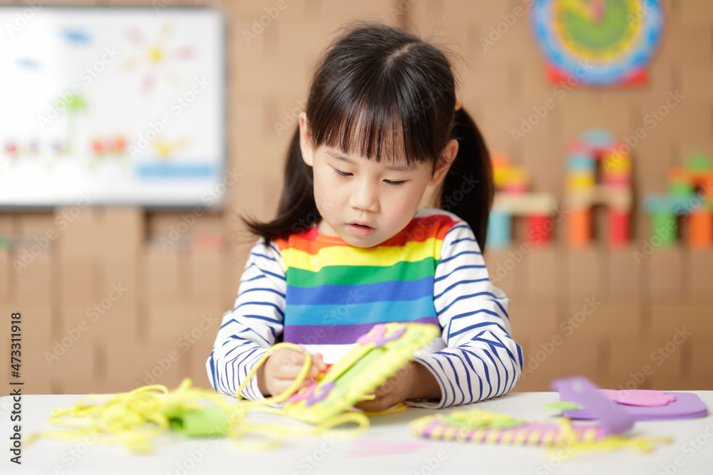 young girl sewing pad craft using plastic needle and yarn at home young girl sewing pad craft using plastic needle and yarn at home