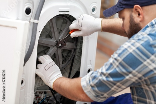 a man repairing a washing machine in cap