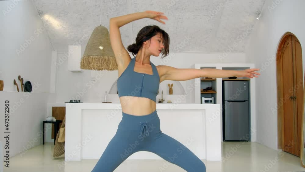 attractive European brunette girl makes a yoga in a white bright room on a yoga mat. Do sports at home alone.