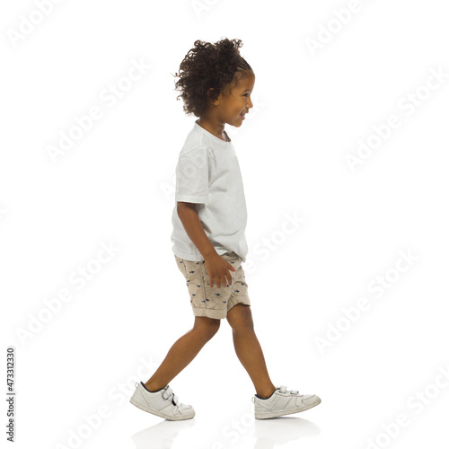 Sneaking little black boy. Side view. Full length, isolated.