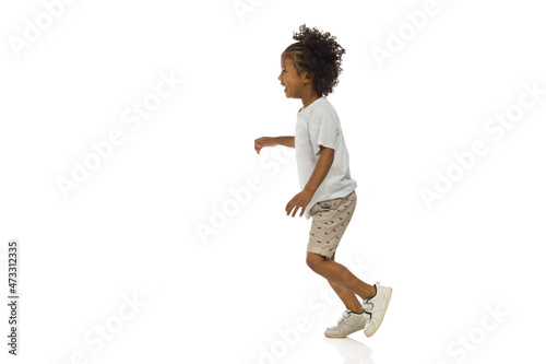 Smiling little black boy is running. Side view. Full length, isolated.