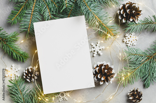 Christmas greeting card mockup with lighting garlands and fir tree branches with cones