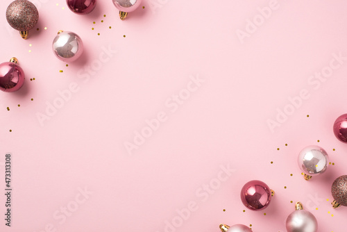 Top view photo of pink christmas tree decorations balls and gold sequins on isolated pastel pink background with copyspace © ActionGP