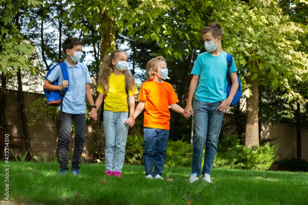Group of schoolchildren in masks walking together on the park Group of schoolchildren in masks walking together on the park