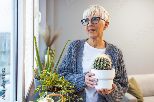 Active senior woman enjoying planting. Senior woman planting flowers. Senior woman plant care at home. Portrait Of Happy Mature Arranging Potted Plants. Senior Woman With Green Plants 