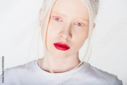 Portrait of albino woman with red lips in white t-shirt looking at camera isolated on white. photo