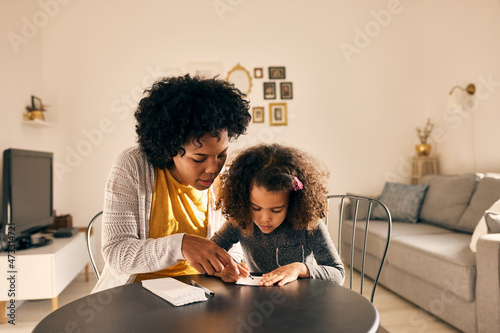 Supportive adult mother, drawing with her daughter, at home.