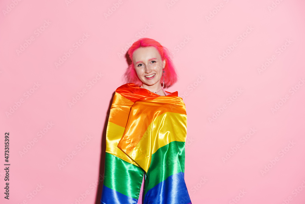 Shirtless woman smiling while posing with rainbow flag