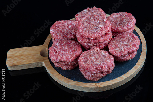Raw beef meatballs made with various homemade spicy, beef kofta kofta raw, on black ground.