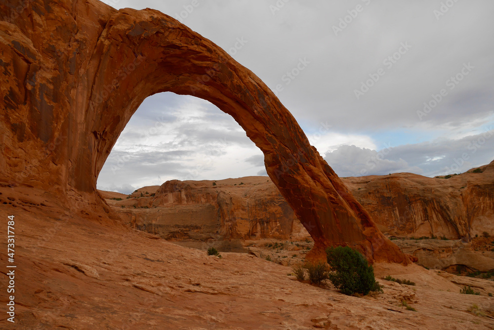 Corona Arch near Moab at sunset after thunderstorm. Typical Utah red rock formations.