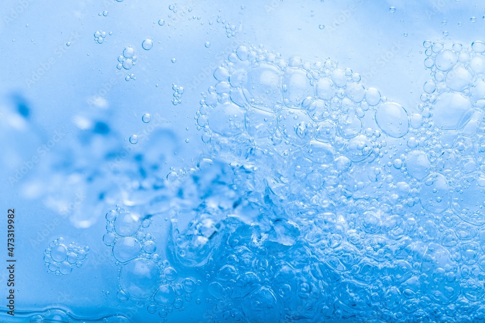 Blurred blue clear calm water surface texture with splashes and bubbles. abstract nature background. Water waves.