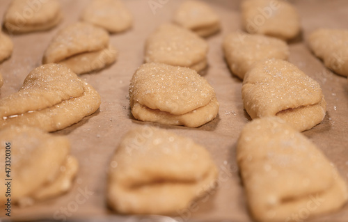Cookie blanks from cottage cheese dough sprinkled with sugar on a sheet of baking paper