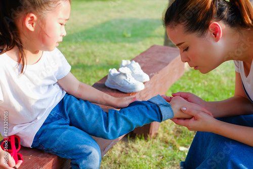 Family take care small child girl naughty in park until her have lesion on the feet