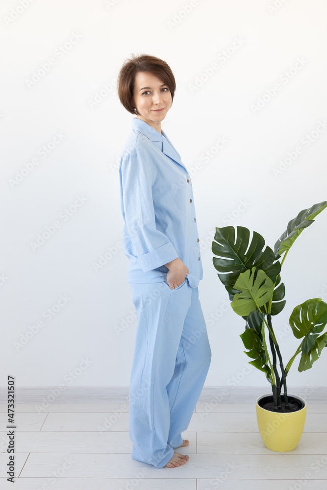 Young attractive woman dressed in beautiful colorful pajama posing as a model in her living room. Comfortable sleepwear, home relaxation and female fashion concept.