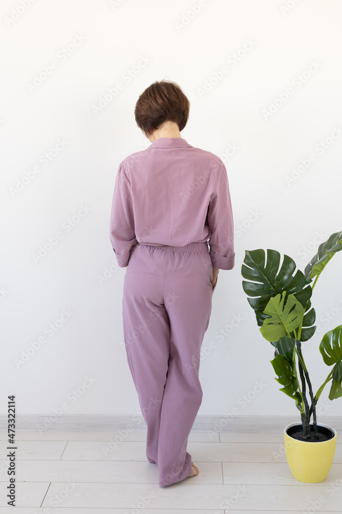Back view of woman dressed in beautiful colorful pajama posing as a model in her living room. Comfortable sleepwear, home relaxation and female fashion concept.
