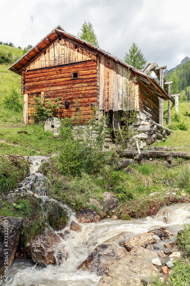 Ancient water mill on the banks of a mountain stream in a park Mill Valley (Val di Morins). Longiaru, Italy (Vertical photo) Ancient water mill on the banks of a mountain stream in a park Mill Valley (Val di Morins). Longiaru, Italy (Vertical photo)