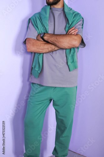 A guy in a stylish, cozy sportswear against a bright background, studio shooting for a magazine, details of fabrics and flowers