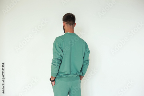 A guy in a stylish, cozy sportswear against a bright background, studio shooting for a magazine, details of fabrics and flowers