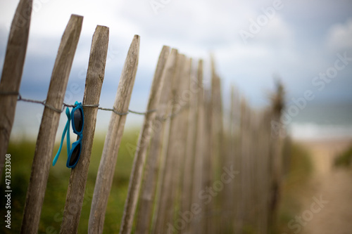 Closeup of lost glasses in the dunes of Soulac-sur-Mer in Médoc, France with the Atlantic Ocean in the background on a cloudy summer day at vacation photo