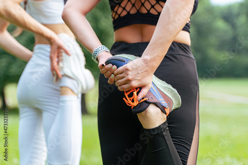 Two girls do a warm-up, stretching in the park before running.