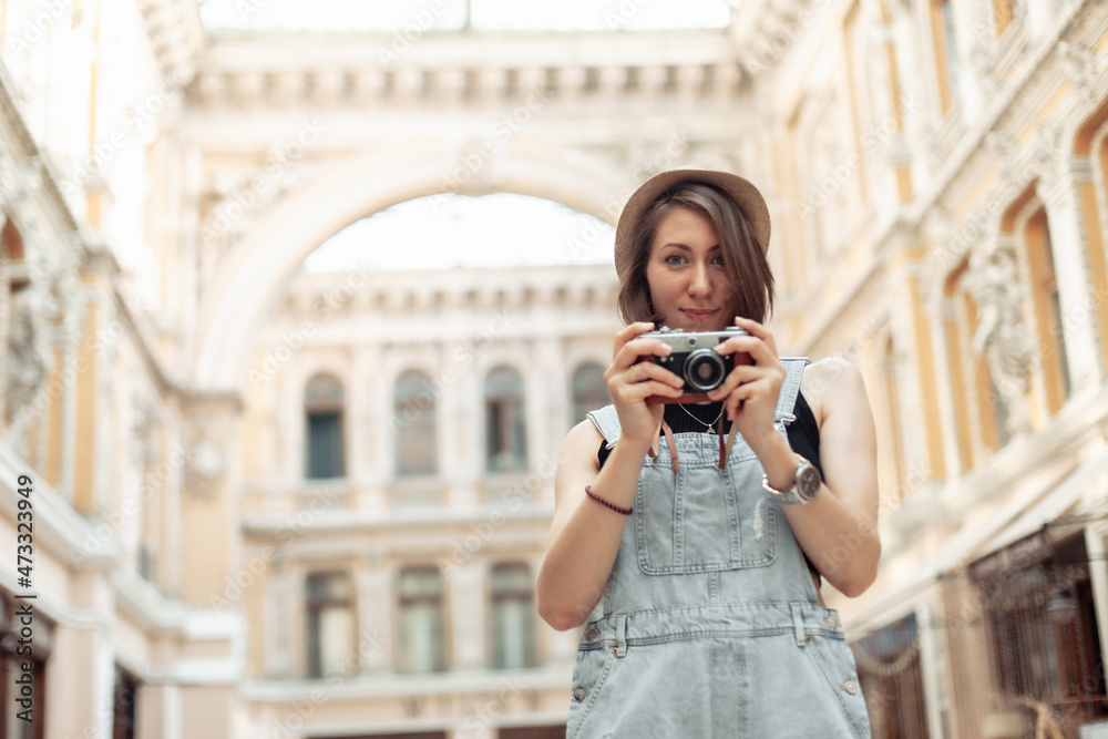 Young stylish woman tourist with retro camera in European city architecture. Travel concept