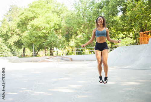 Athletic woman with perfect body jumping rope outdoors