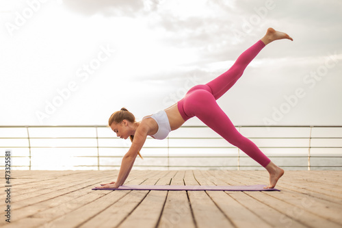 Young beautiful woman is practicing yoga asana on the beach. Healthy lifestyle. Yoga practice