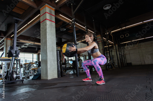 Fit woman is exercising with medicine ball in modern gym. Strong body
