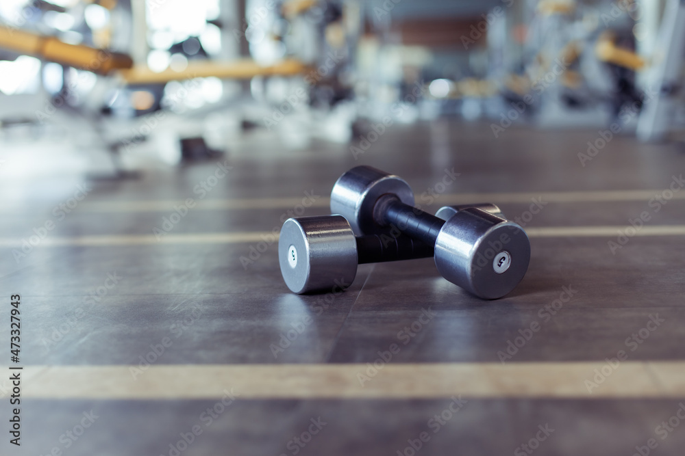 Metal dumbbells on the gym floor. Bodybuilding and fitness concept Metal dumbbells on the gym floor. Bodybuilding and fitness concept