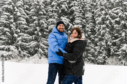 Walk in winter. Embracing couple enjoying snowfall. Man and woman having fun in the frosty forest. Romantic date in winter time.Christmas mood of a young family.  Love and leisure concept © Vadym