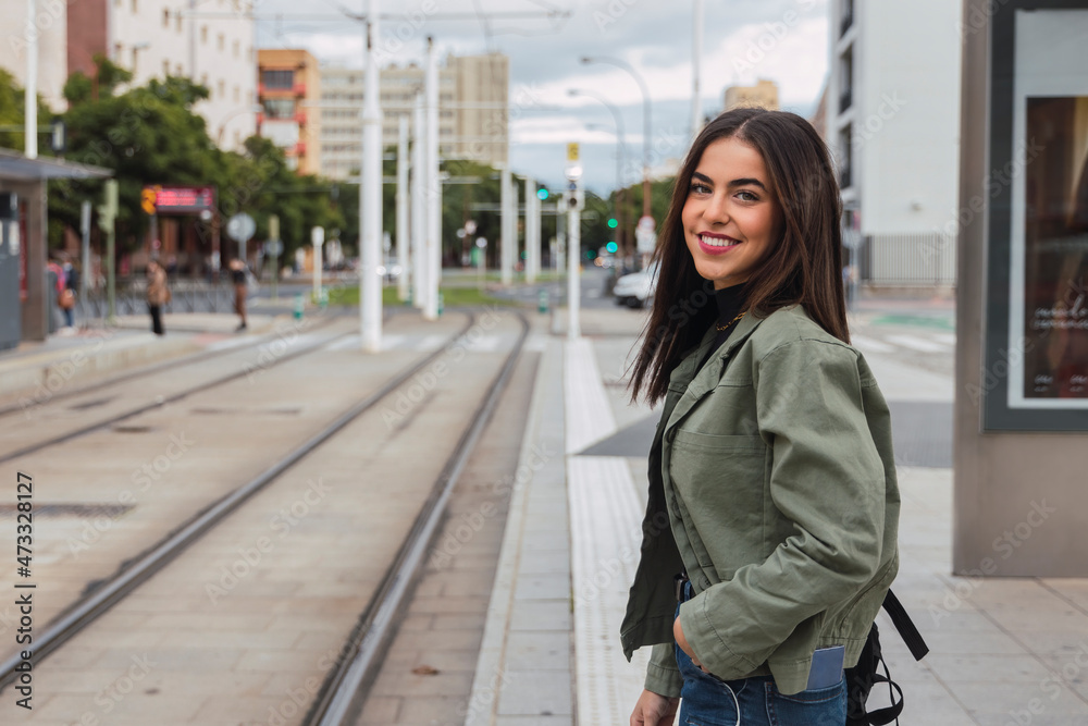Smiling woman with hand in pocket at tram station Smiling woman with hand in pocket at tram station