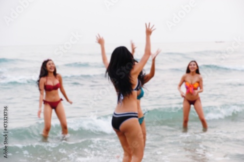Blurred sexy bikini asian women wearing swimwear playing with friends in seaside on the beach