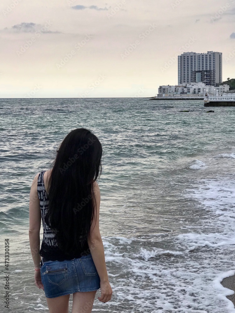 Girl with extremly long dark hair walking near the seaside, finding solitude in nature, recreation, thinking, dreaming, deep in thoughts, loneliness.