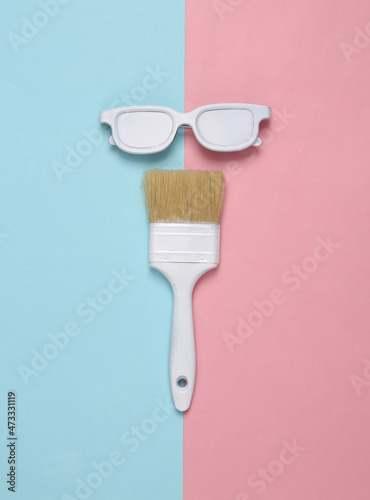 White glasses with paint brush on a blue pink background. Creative layout