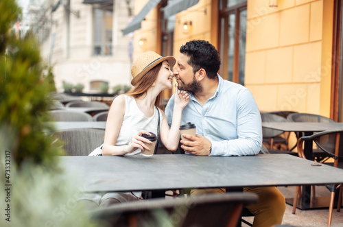 International couple in love drinking coffee while sitting at table in outdoor cafe