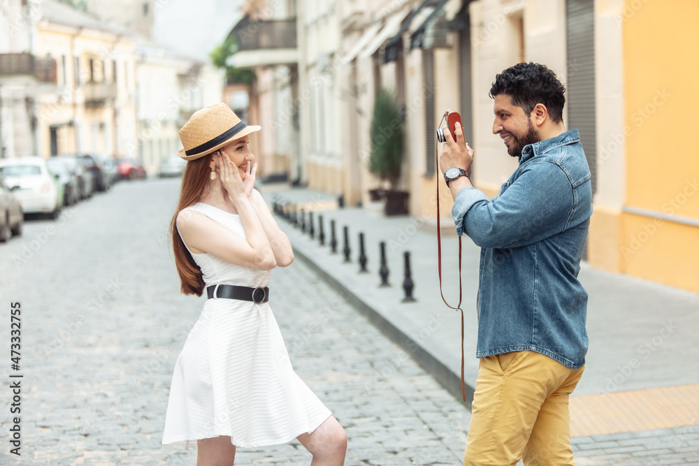 Naklejka premium Hispanic man photographs woman on European street. Tourism, travel concept