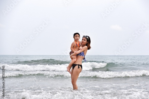asia single mom and daughter happy life on the beach, travel the sea in rayong thailand