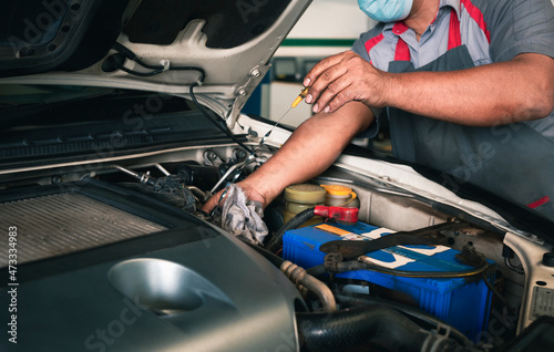 Auto mechanic working check the oil level in car engine in garage. Repair service.