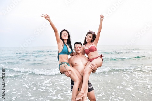 handsome man carry ladies wearing bikini in seaside on the beach