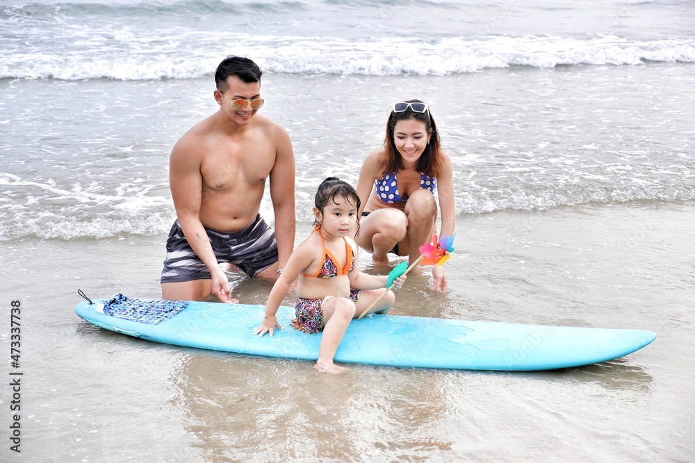 Obraz premium asia family father and mother and daughter happy life on the beach with surfboard, travel the sea in rayong thailand